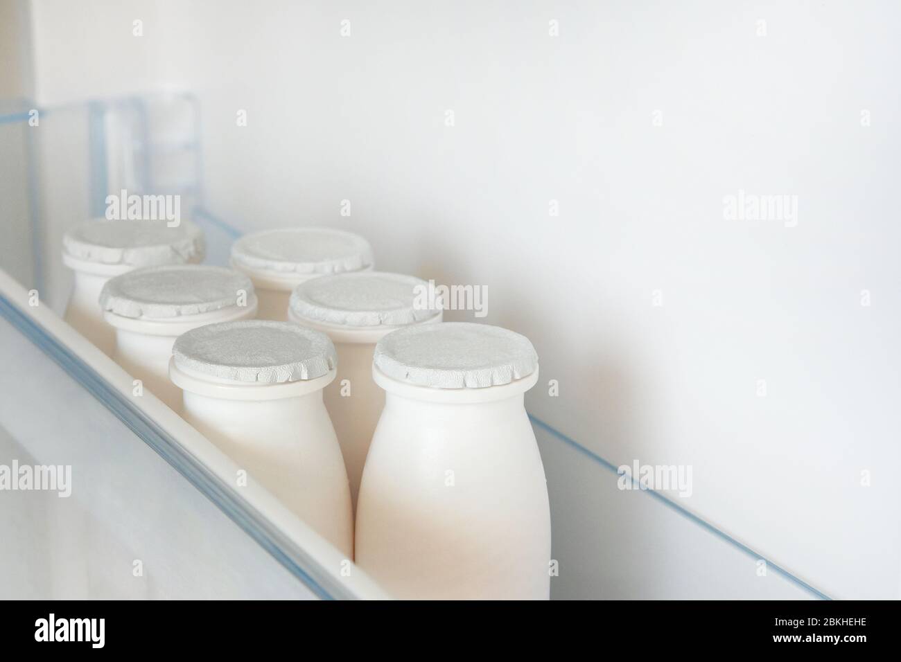 Bouteilles blanches de produits laitiers sur la tablette du réfrigérateur vide ouvert. Concept de régime de perte de poids. Banque D'Images