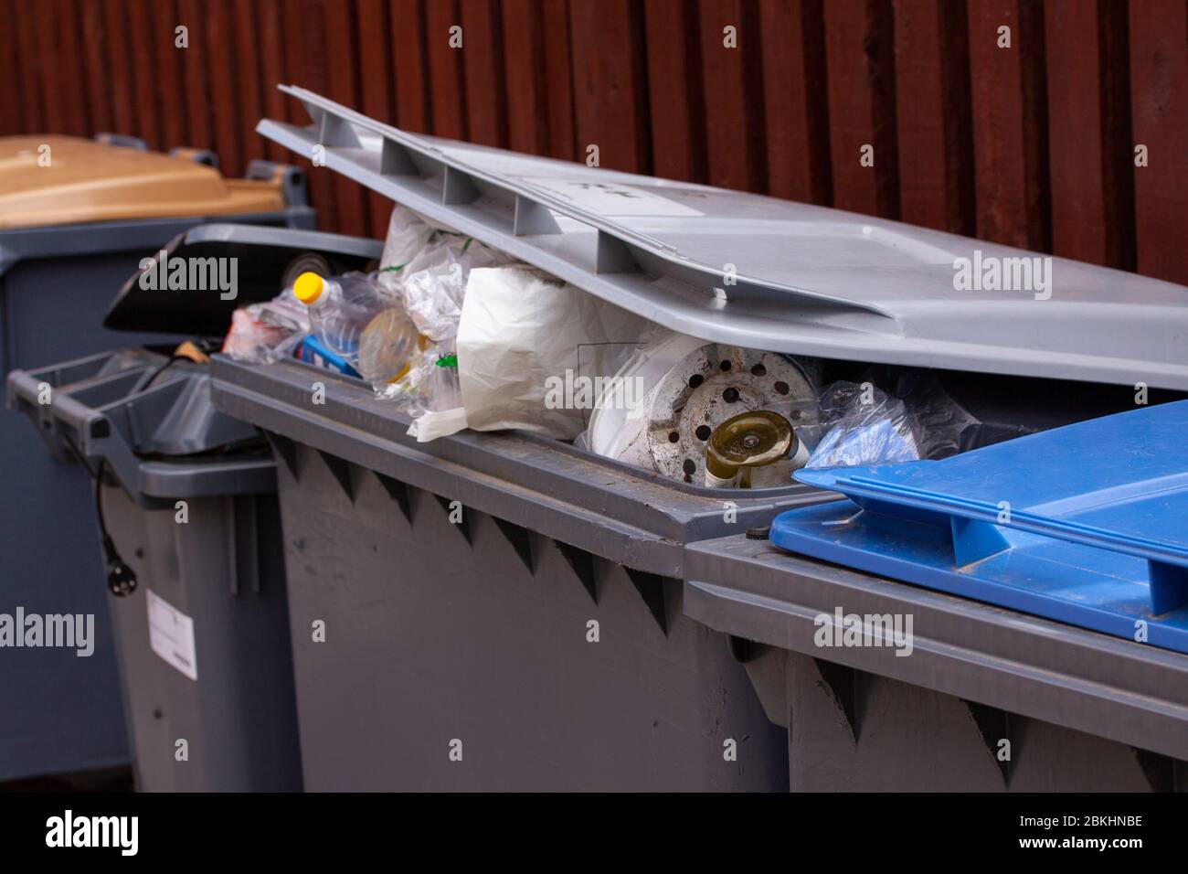 Les grandes poubelles à roues avec leurs langes sont trop remplies de déchets comme les ordures ménagères, les ordures, le recyclage et les déchets de jardin. Banque D'Images