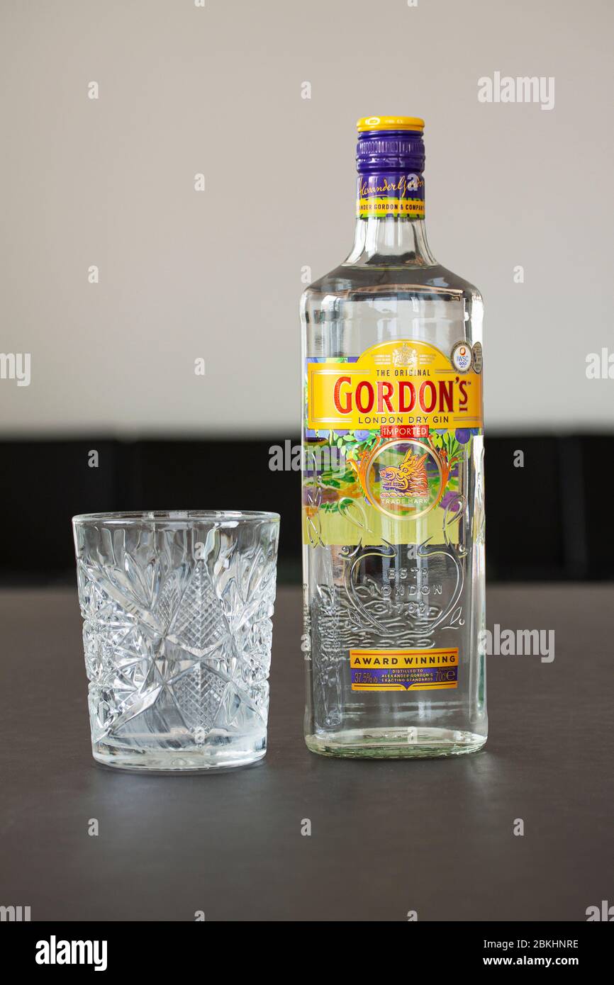 Une bouteille de Gin de Gordon et un verre de cristal sur une table. Gordon est une marque du gin sec londonien le plus vendu au monde, propriété des British Spirits c Banque D'Images