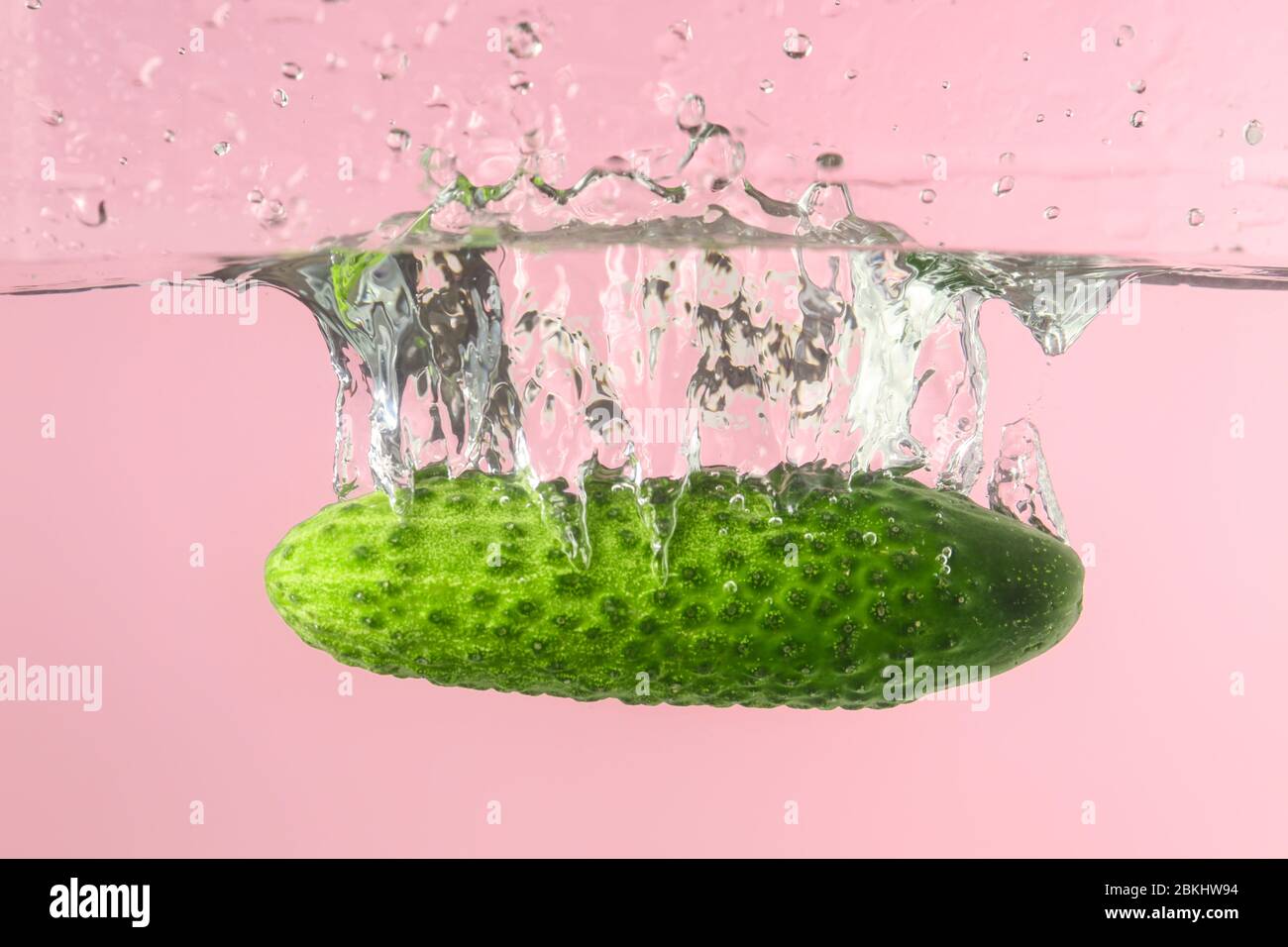 Chute de concombre frais dans l'eau sur fond de couleur Banque D'Images