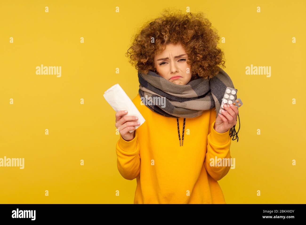 Traitement de la grippe. Contrarié déprimé de la grippe-malade avec des cheveux bouclés, enveloppé dans une écharpe chaude, tenant la serviette et les pilules, frognant avec mérab déplaisés Banque D'Images