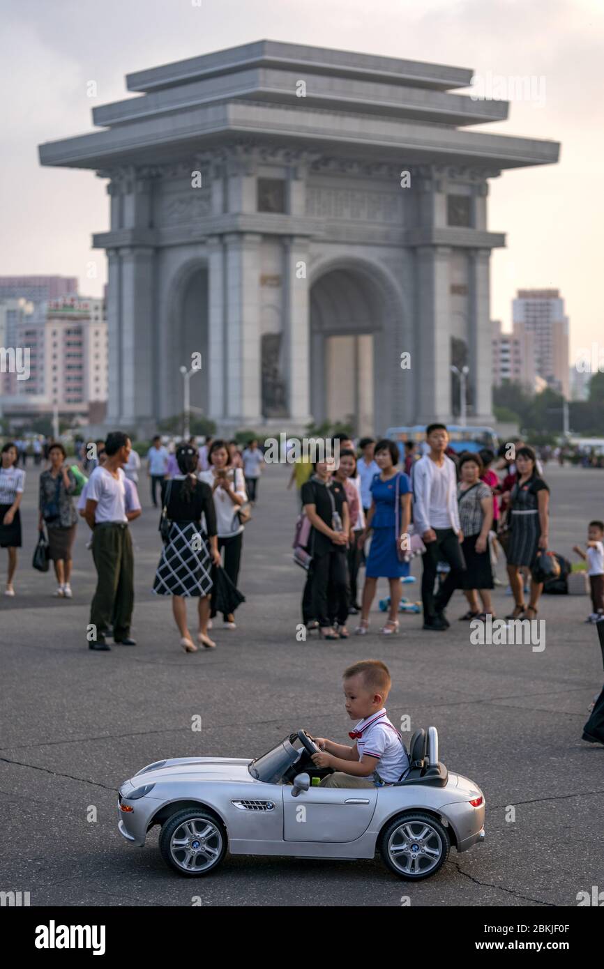 Corée du Nord, Pyongyang, enfant jouant avec une voiture BMW filaire devant l'Arc de Triomphe Banque D'Images