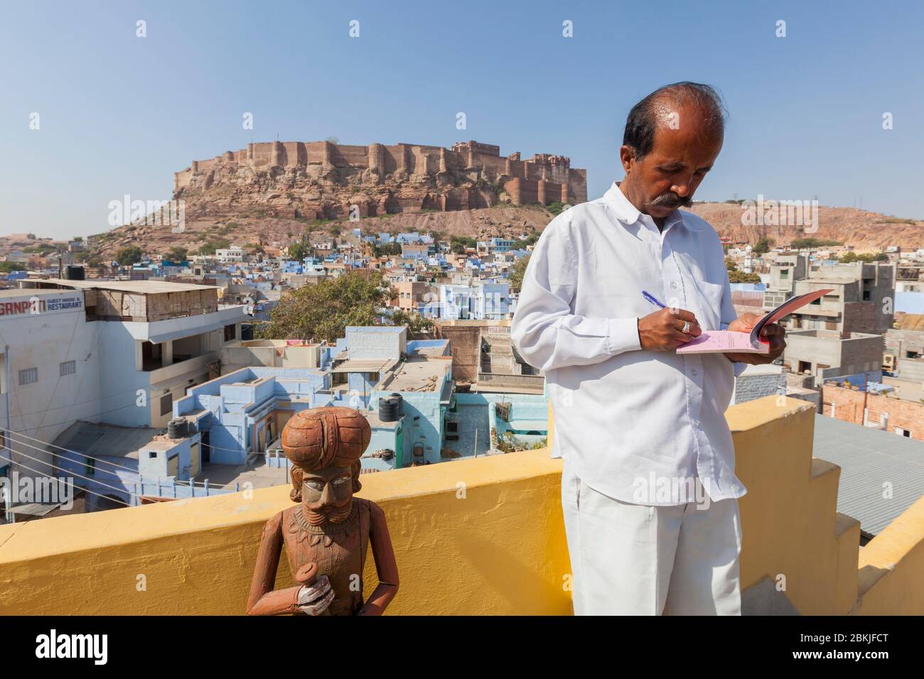 Inde, Rajasthan, Jodhpur, serveur sur le restaurant Haveli Guest House sur le toit et fort Mehrangarh en arrière-plan Banque D'Images