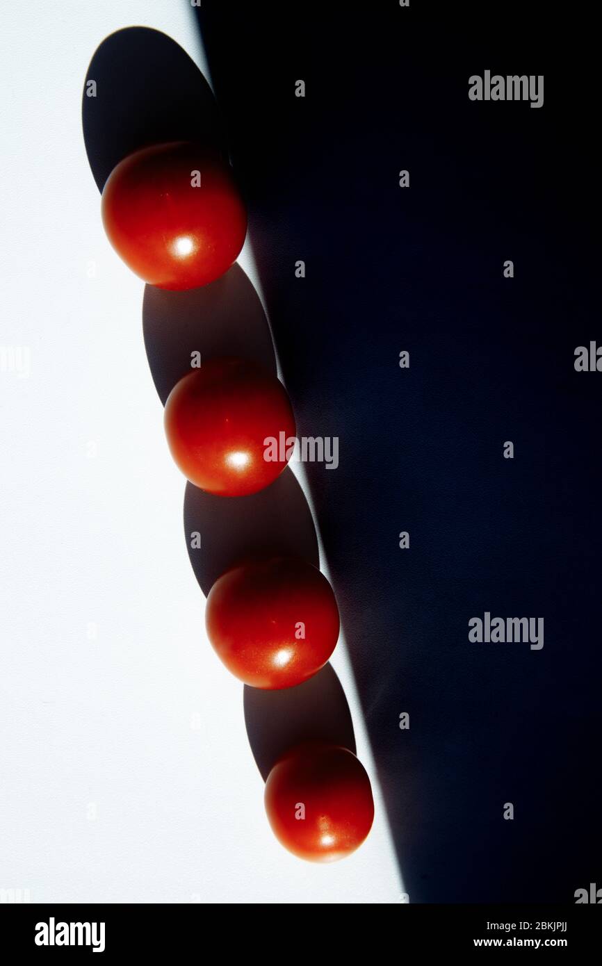 Quatre tomates rouges sont empilées l'une après l'autre, une ombre sombre tombe d'elles. Banque D'Images