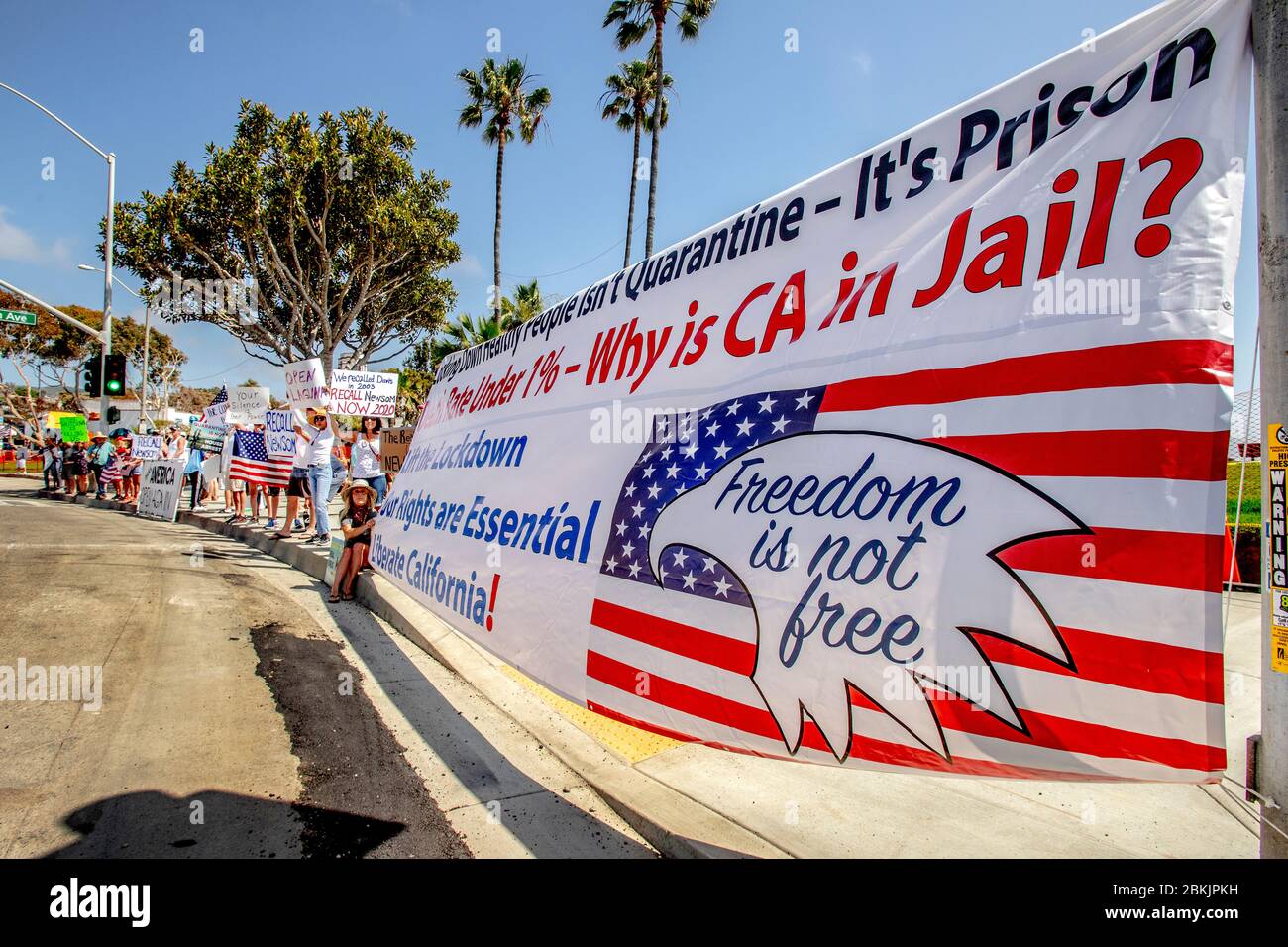 Touchant une posture patriotique, des manifestants multiraciaux s'opposent à l'ordre de confinement du gouverneur de Californie, Gavin Newsom, pour combattre la pandémie du coronavirus/COVID-19, qui se rassemblent sur la Pacific Coast Highway à Laguna Beach, en Californie. Banque D'Images