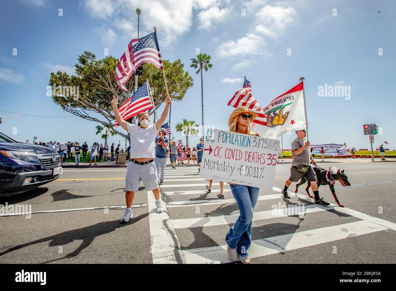 Touchant une posture patriotique, des manifestants multiraciaux s'opposent à l'ordre de confinement du gouverneur de Californie, Gavin Newsom, pour combattre la pandémie du coronavirus/COVID-19, qui se rassemblent sur la Pacific Coast Highway à Laguna Beach, en Californie. Banque D'Images