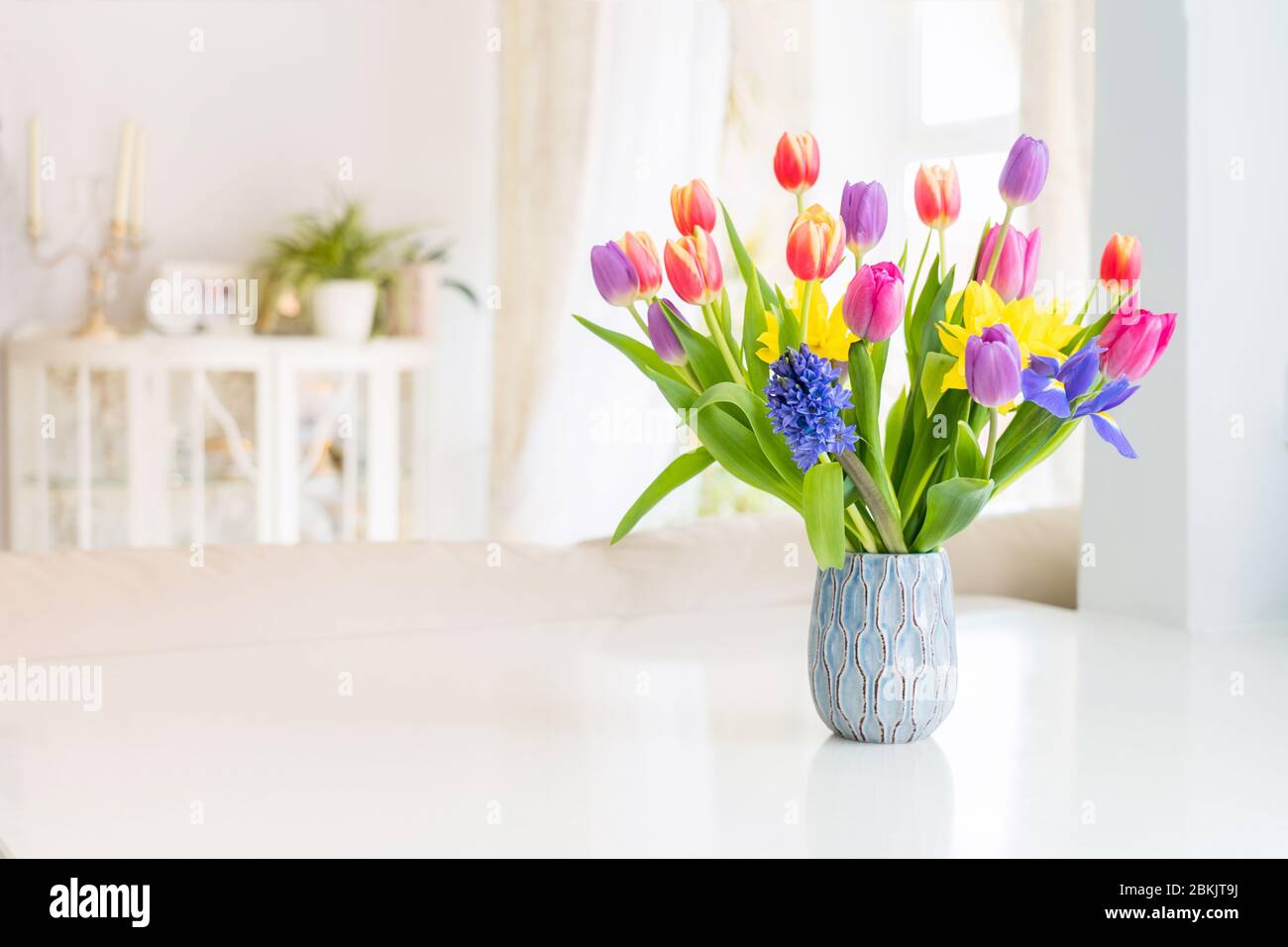 Printemps frais bouquet coloré de tulipes, jonquilles, iris dans vase  debout sur table en marbre blanc avec un décor clair classique salon  arrière-plan. FE Photo Stock - Alamy