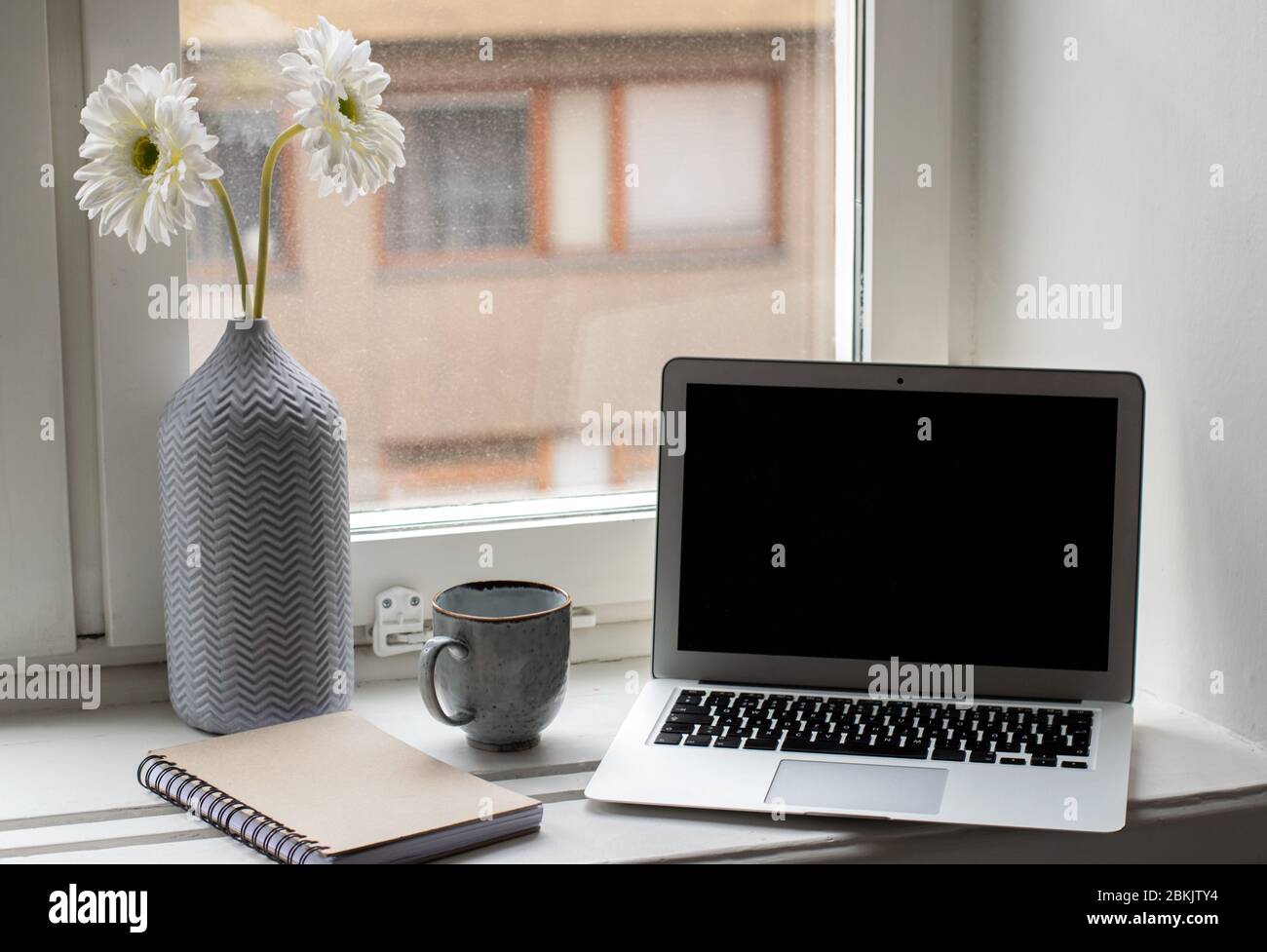 Un espace de travail moderne et lumineux avec fleurs, ordinateur portable, ordinateur portable et café Banque D'Images