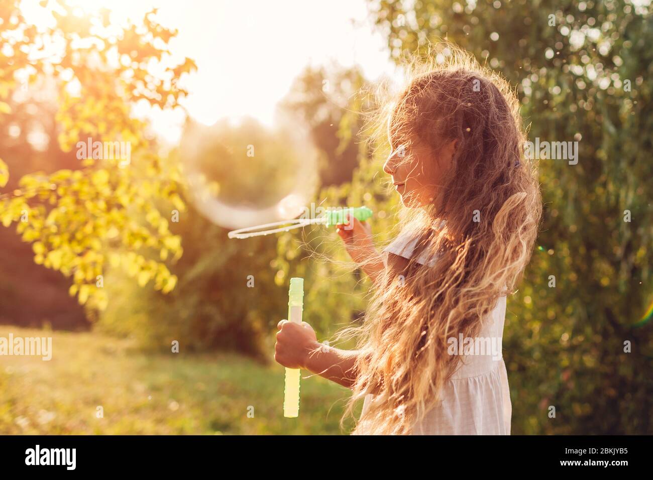 Petite fille mignonne soufflant des bulles dans le parc de printemps. Enfant s'amusant à jouer à des jeux en plein air. Activités pour enfants Banque D'Images