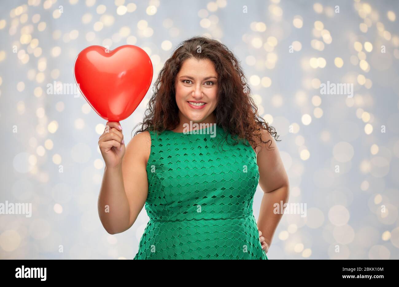 Happy woman holding red heart shaped balloon Banque D'Images