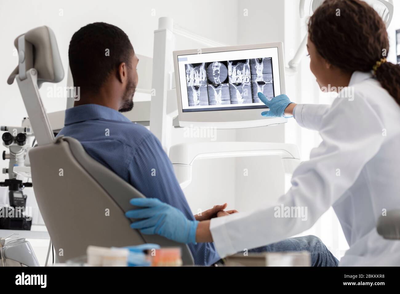Dentiste féminin et patient masculin regardant des rayons X sur écran numérique Banque D'Images