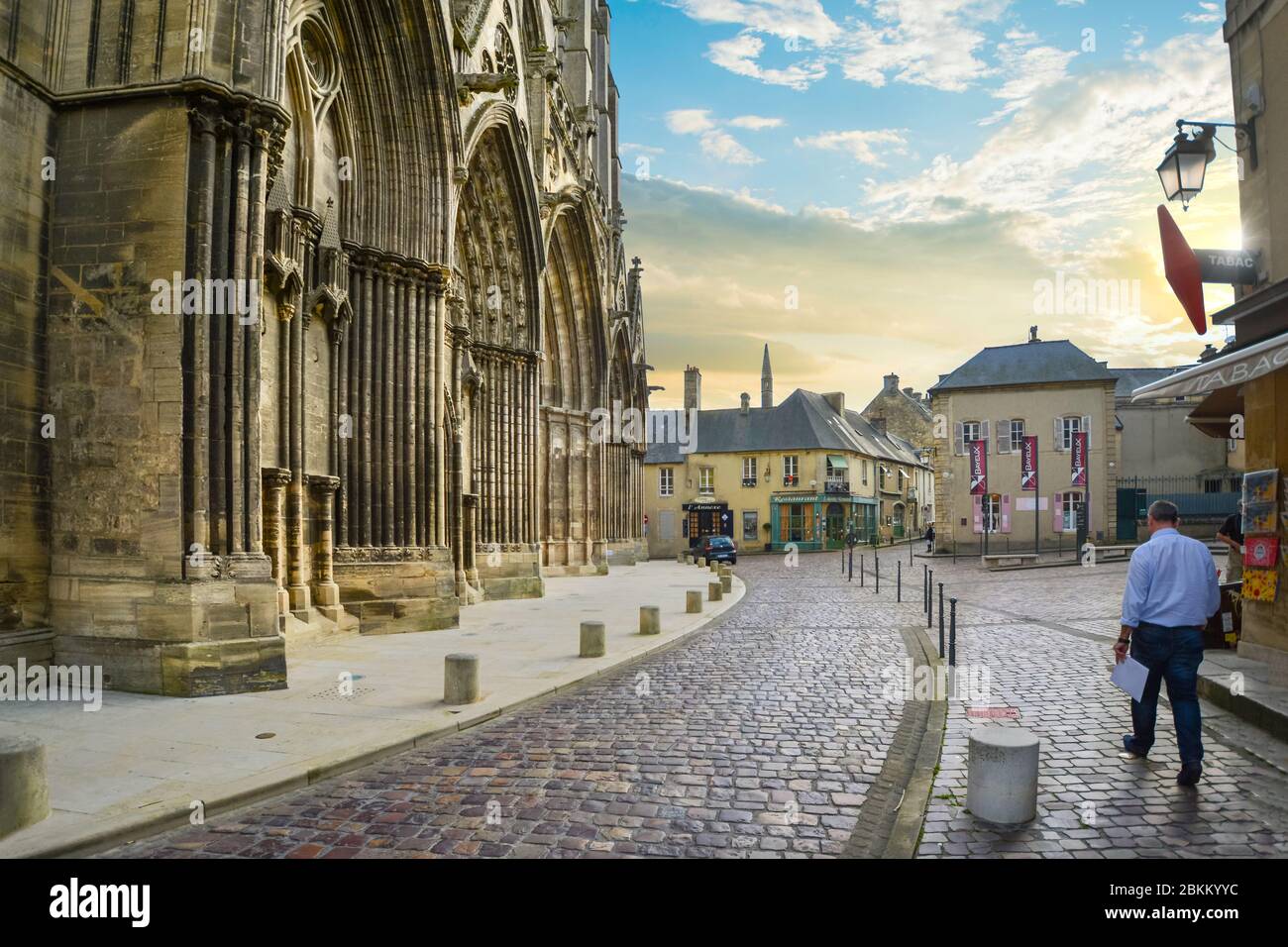 Un homme marche devant le Bayeux gothique, la cathédrale dans le village normand de Bayeux, en France. Banque D'Images