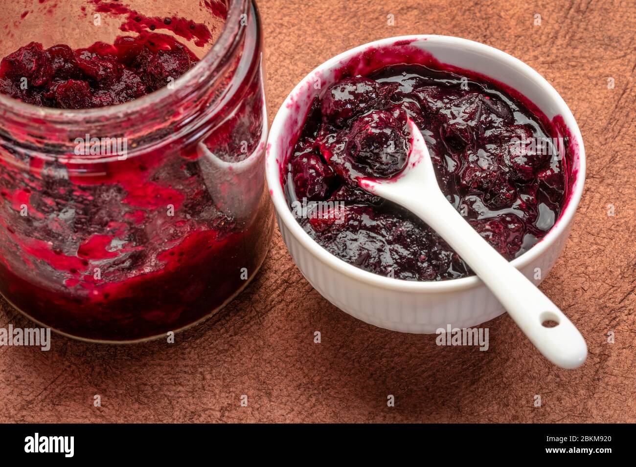 sauce aux canneberges entières maison - bol en verre et petit bol en céramique sur un papier texturé Banque D'Images