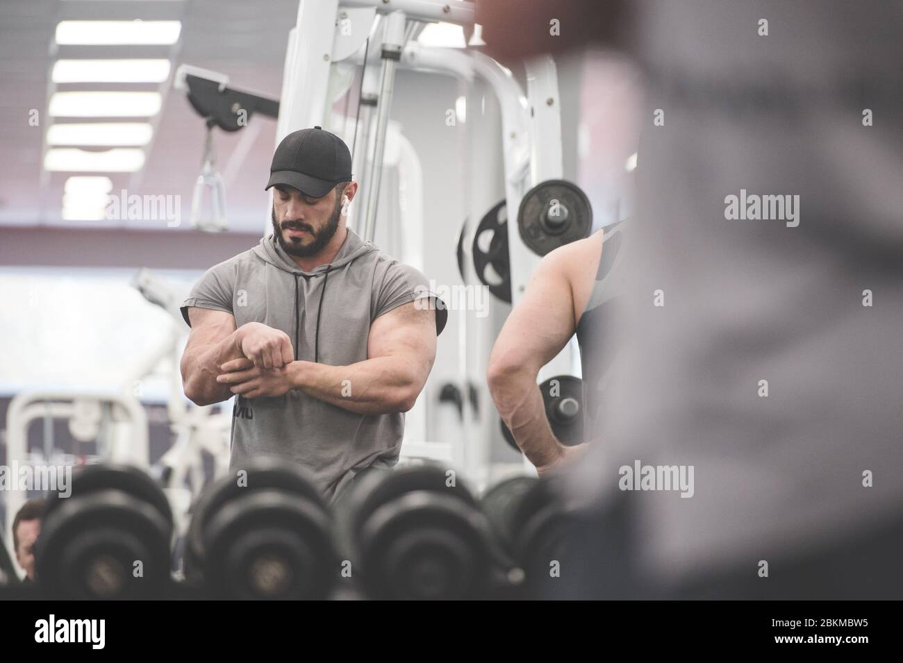 sport blessure concept de jeune athlète fort barbu homme tenant son poignet douloureux avec la main souffrant de douleur pendant l'entraînement avec les gens Banque D'Images