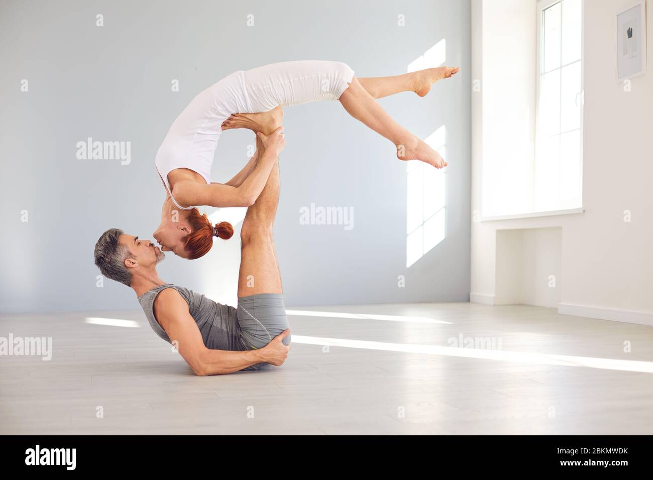 Un couple de yoga pratique le yoga acro sur le sol dans un cours de studio. Banque D'Images