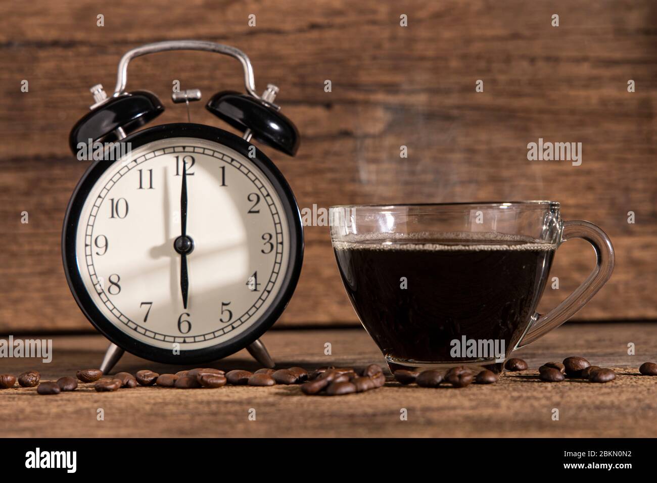 Une tasse de café et de grain de café avec horloge sur fond de table en bois. Banque D'Images