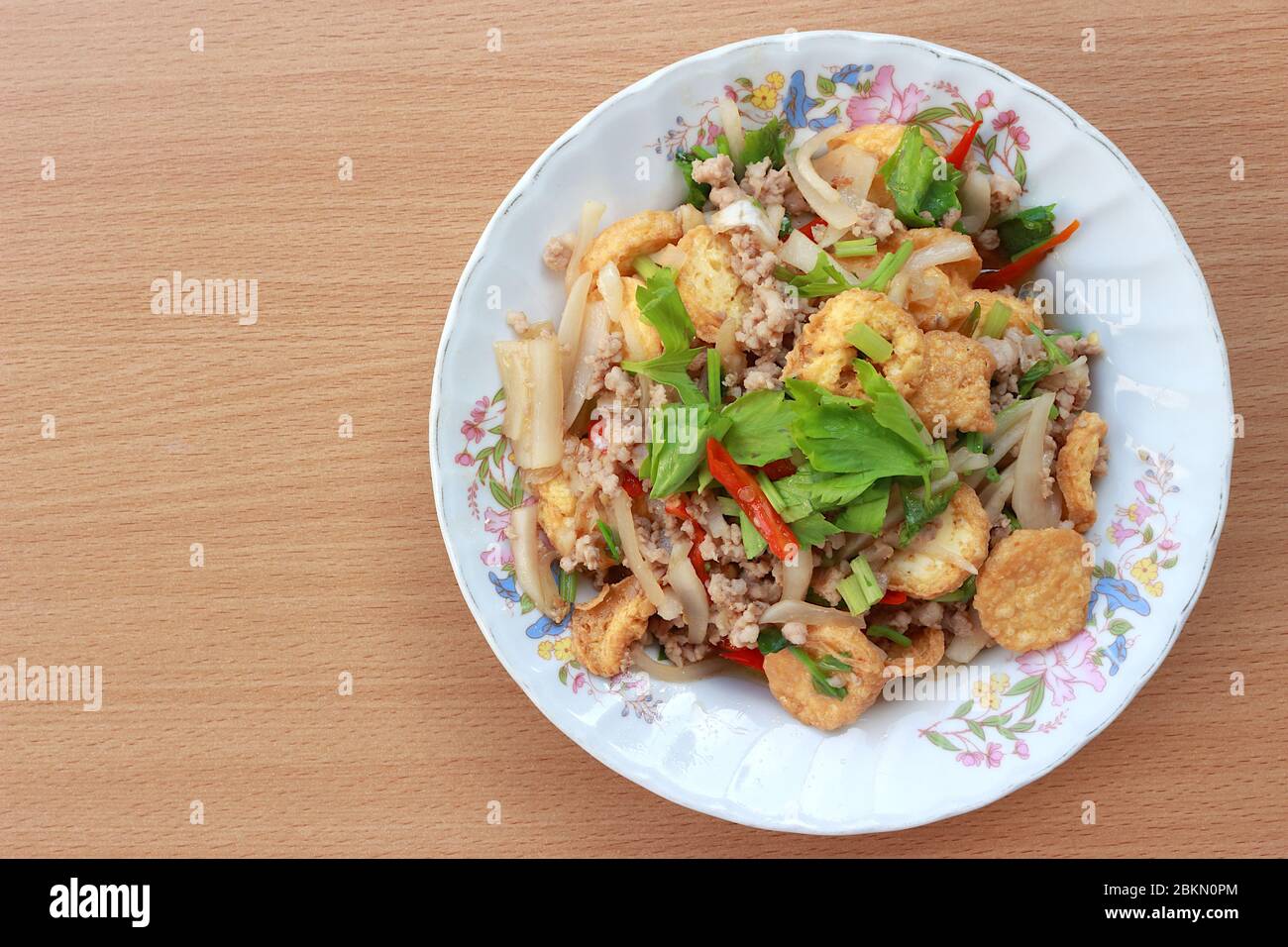 Image de la vue de dessus. Remuez le tofu frits avec une purée de porc, d'oignon, de céleri, de coriandre et un peu de piment frais. Placez-le dans une assiette blanche à motifs floraux et placez-le Banque D'Images