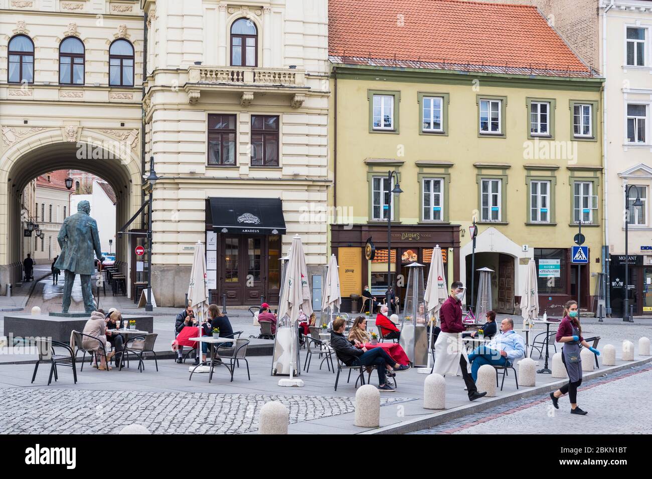 Bar et restaurant en plein air avec clients et serveuse avec masque et gant à Vilnius, capitale lituanienne rouvrant dans la vaste ville de café en plein air Banque D'Images
