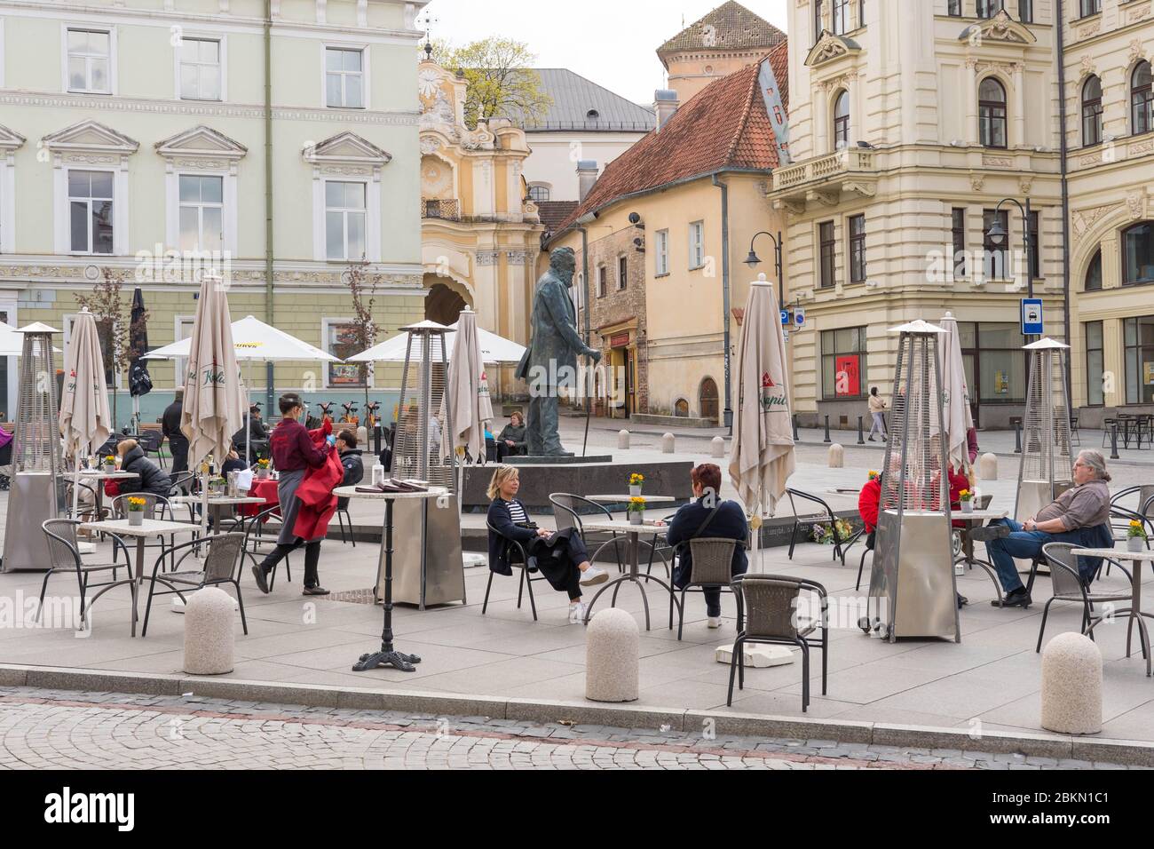 Bar et restaurant en plein air avec clients et serveuse avec masque et gant à Vilnius, capitale lituanienne rouvrant dans la vaste ville de café en plein air Banque D'Images