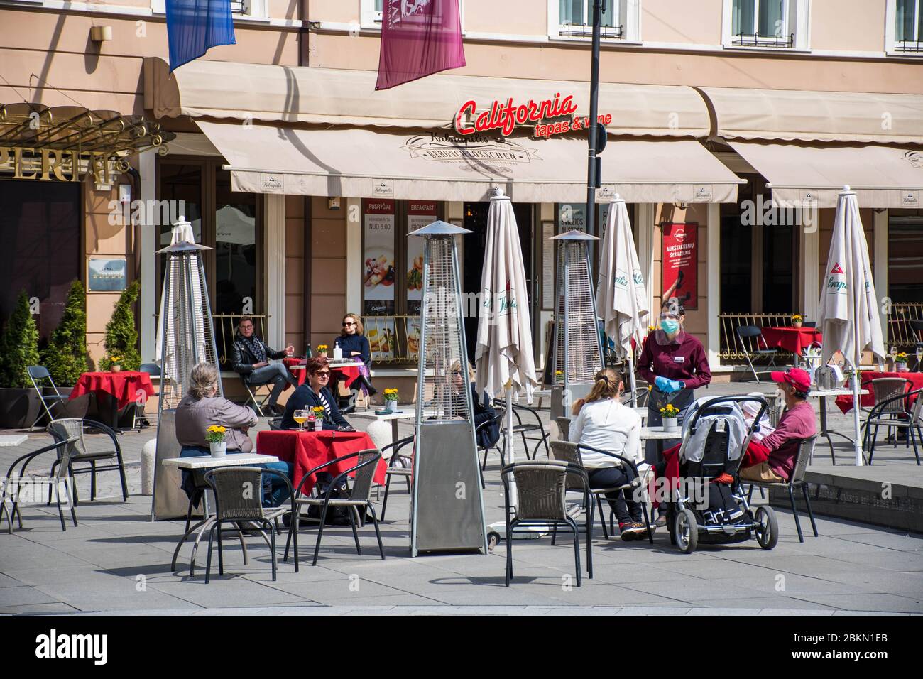 Bar et restaurant en plein air avec clients et serveuse avec masque et gant à Vilnius, capitale lituanienne rouvrant dans la vaste ville de café en plein air Banque D'Images