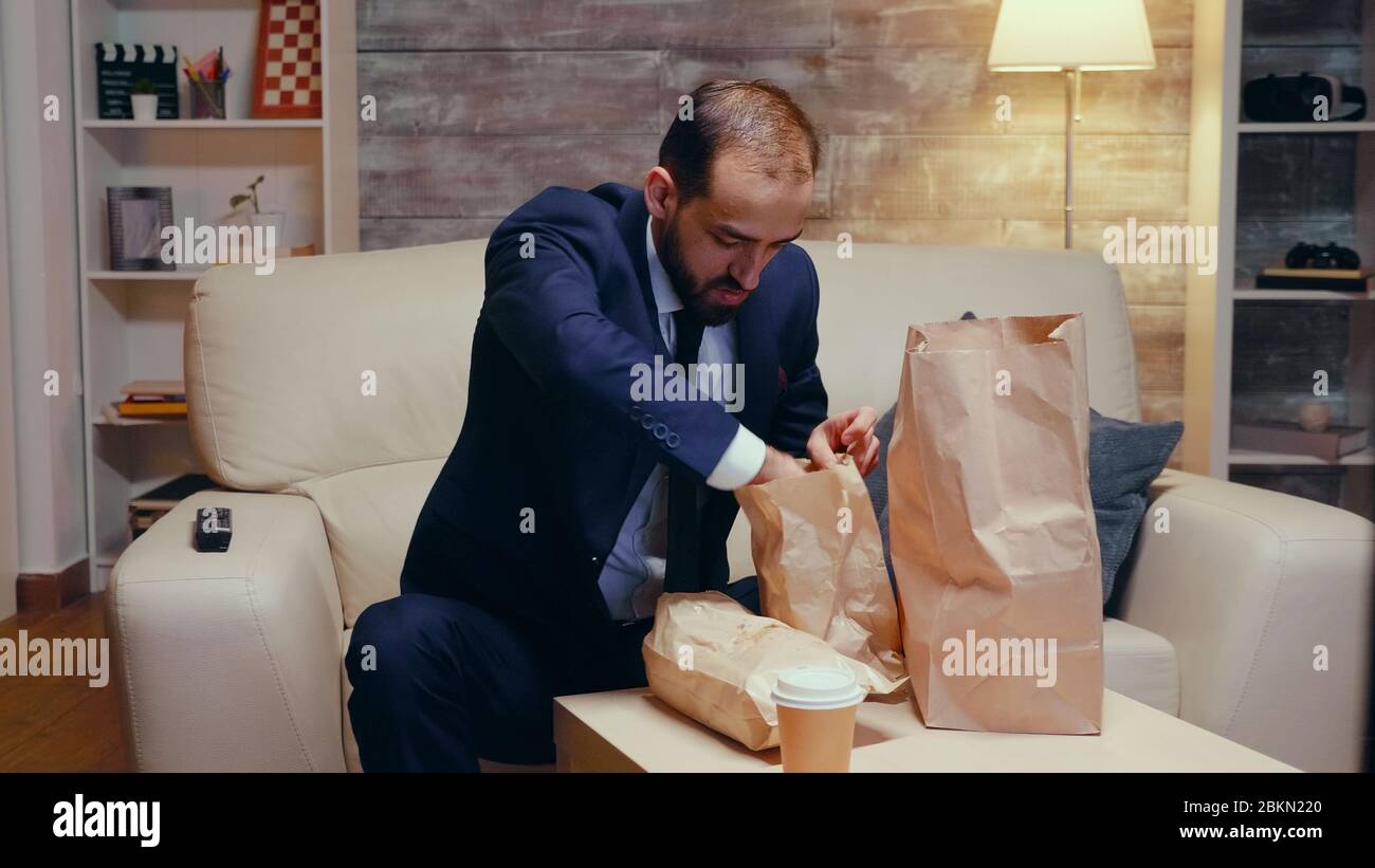 Suivez la photo d'un homme d'affaires affamé qui rentre à la maison avec des plats à emporter. Banque D'Images