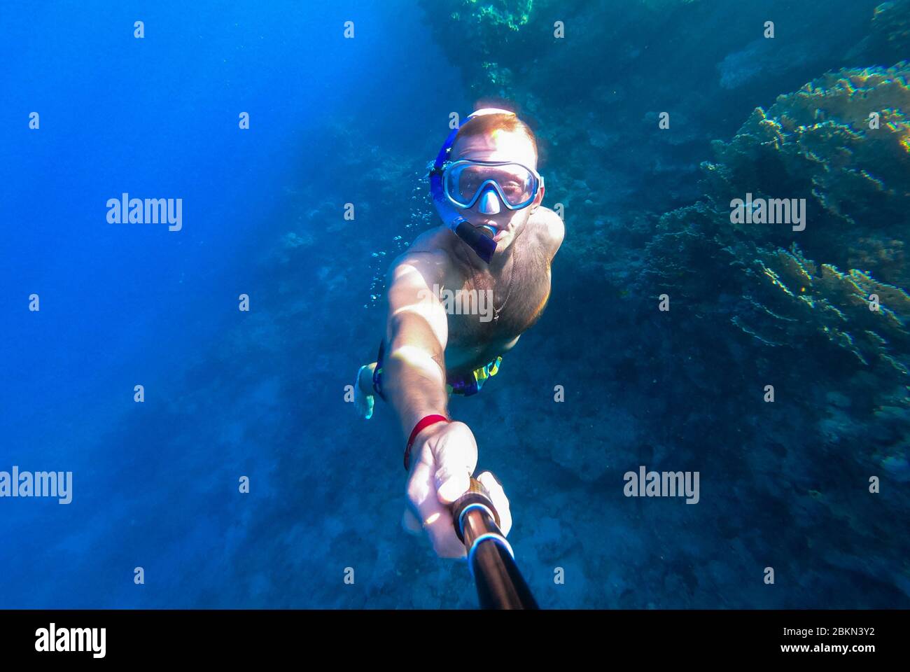 Un gars avec un masque et plongée avec tuba plonge dans l'eau bleue de la  mer Rouge et des photographies lui-même Photo Stock - Alamy