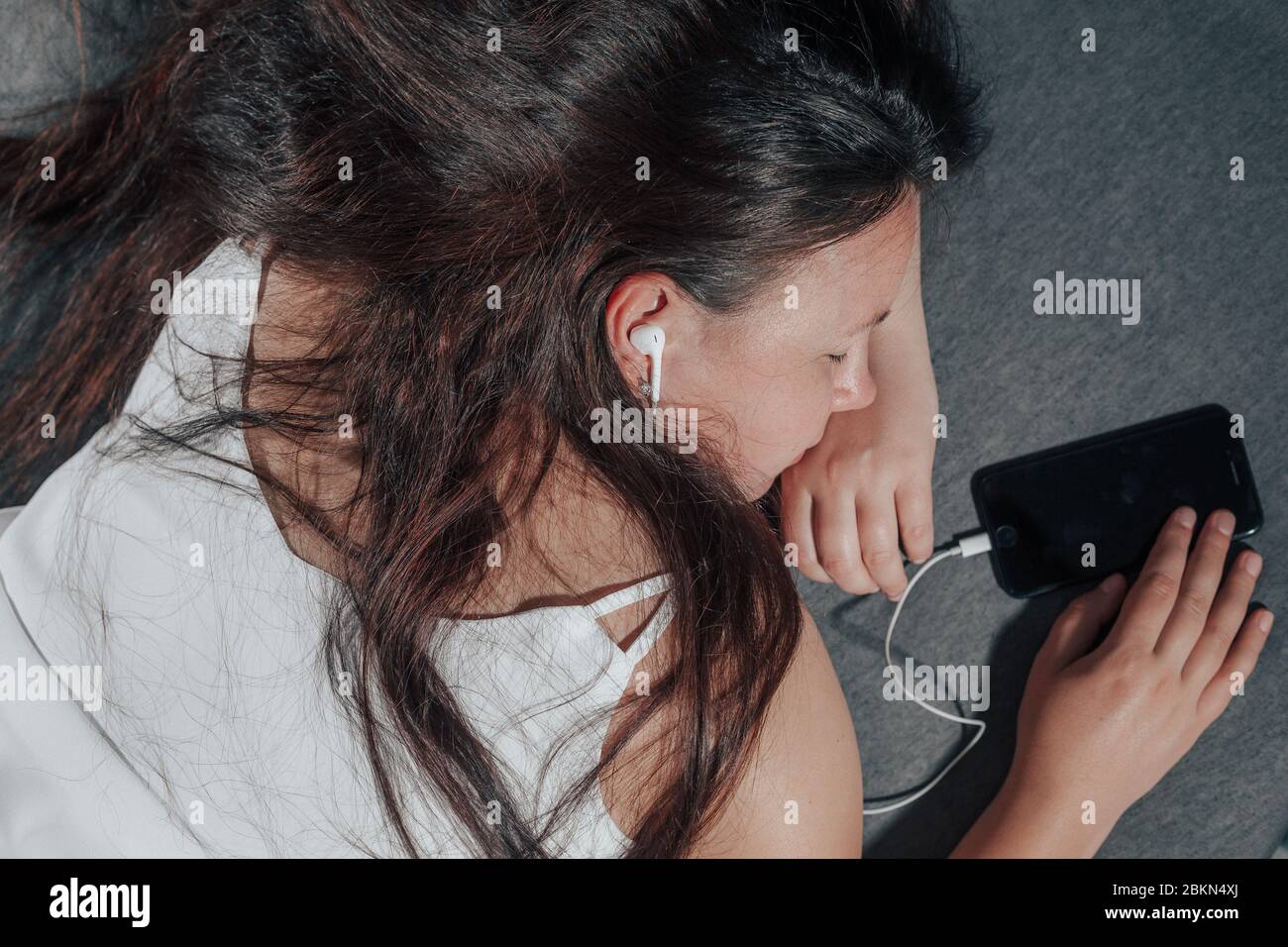 La jeune femme s'est endormi avec un smartphone au lit tout en regardant un film, malsain s'endormant Banque D'Images