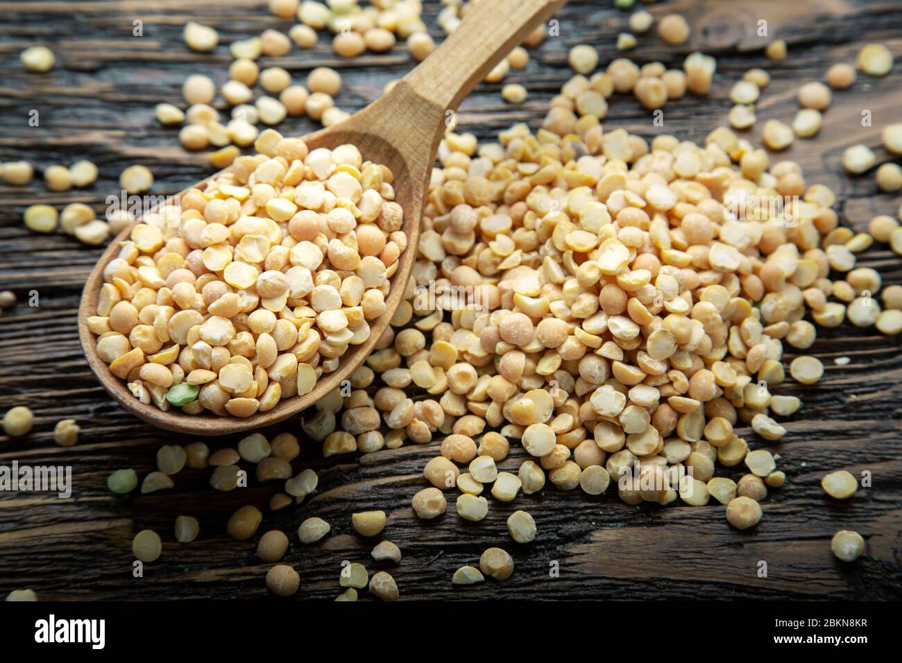 Pois jaunes secs dans une cuillère en bois brun sur un arrière-plan. Les haricots pour soupe nutritive Banque D'Images