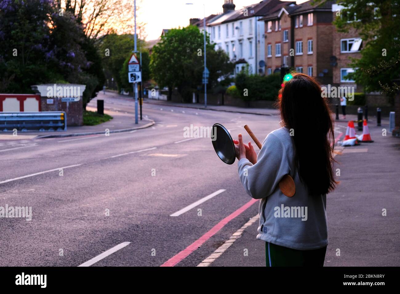Femme se tient dans une rue vide au crépuscule, applaudissant pour le NHS dans le sud de Londres Angleterre Banque D'Images