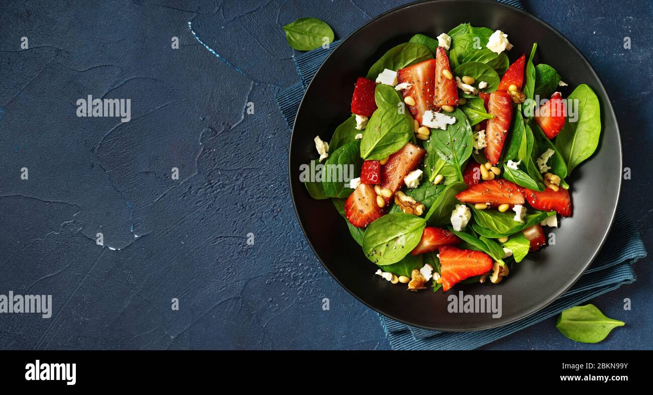 Gros plan de salade de fraises aux épinards, feta ans noix sur fond bleu classique Banque D'Images