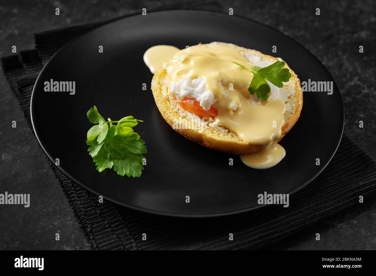 Croise la prise d'œuf poché dans une assiette noire Banque D'Images