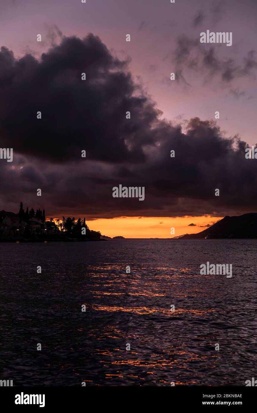 Île de Korcula vue du port pendant le coucher du soleil en été. Belle vieille ville vénitienne avec des montagnes et un ciel pourpre avec la couleur orange profonde crea Banque D'Images