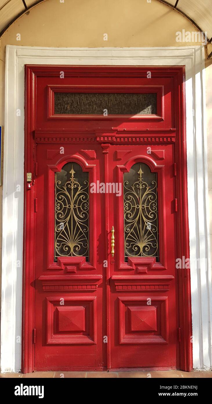Magnifique porte rouge antique avec cadres ornés et grilles métalliques courbées. Patrimoine de bâtiment historique dans la ville européenne Odessa d'Ukraine Banque D'Images