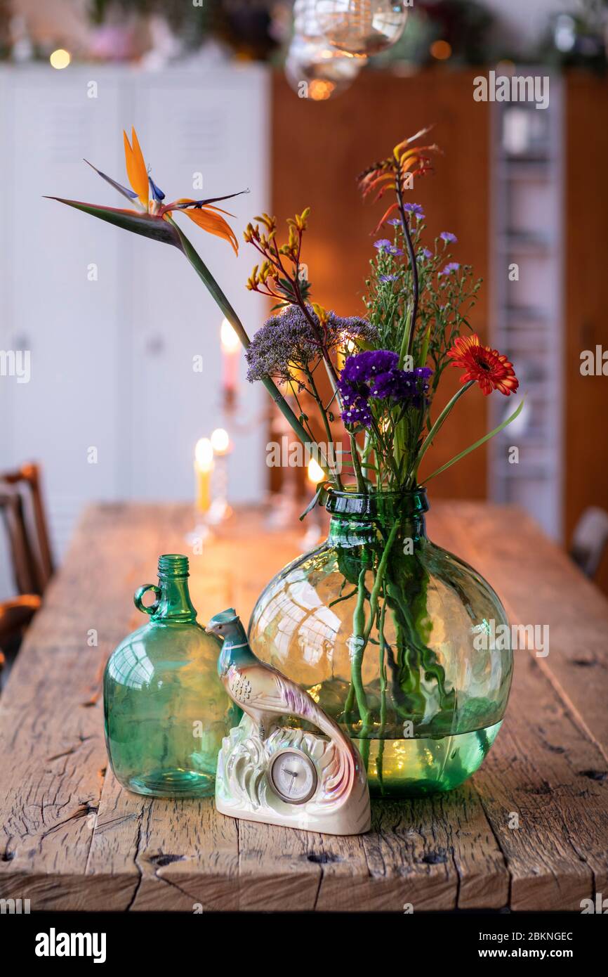 Un détail de vases en verre vert avec des fleurs colorées dans un intérieur  de loft de ville. Une maison bohème, moderne, mélange et s'assortir  éclectique style maison avec un bois rustique