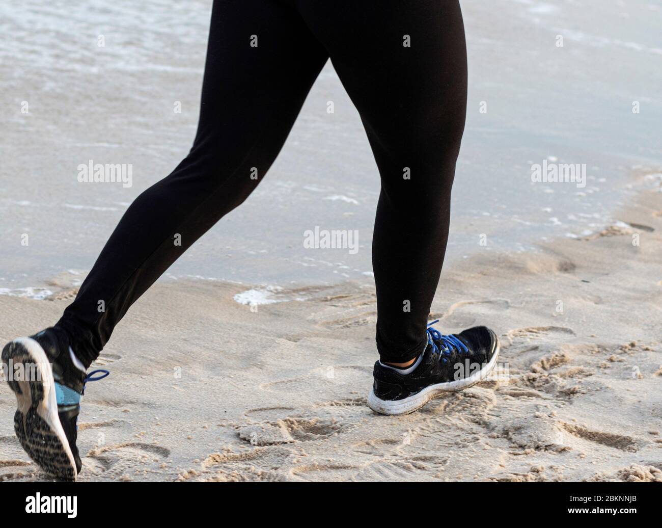Jambes d'un coureur courant sur la plage portant du spandex pendant la série estivale de l'État de New York. Banque D'Images