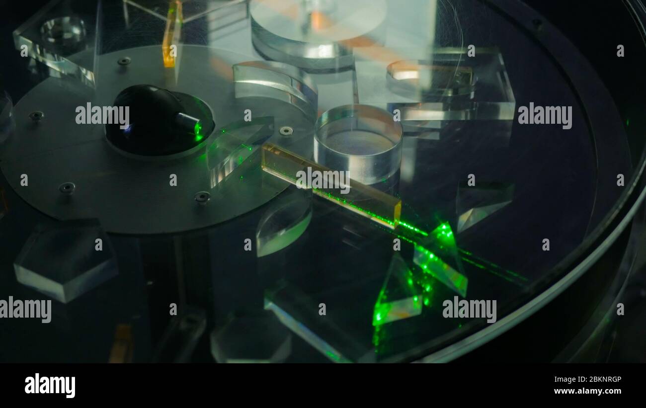 Rayon de lumières laser vertes à travers différentes figures transparentes dans la plate-forme de rotation - effet de réfraction. Optique, expérience et technologie Banque D'Images