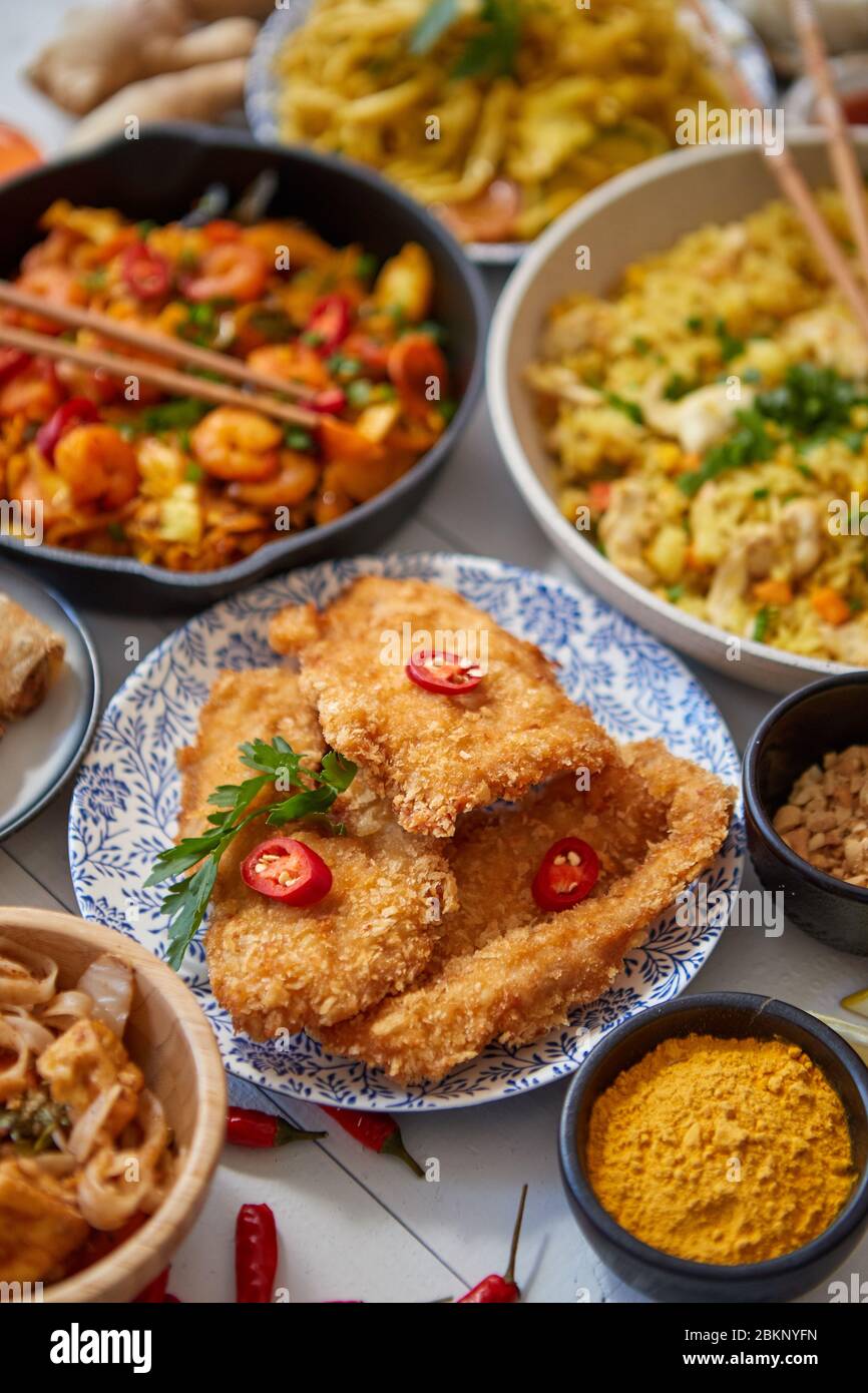Cuisine asiatique servie. Assiettes, casseroles et bols pleins de nouilles sautés de poulet et légumes Banque D'Images