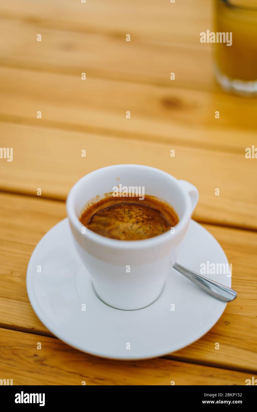 Americano dans une tasse blanche sur une table en bois. Délicieux café du matin dans un café d'été. Tasse blanche avec café sur une assiette. Banque D'Images