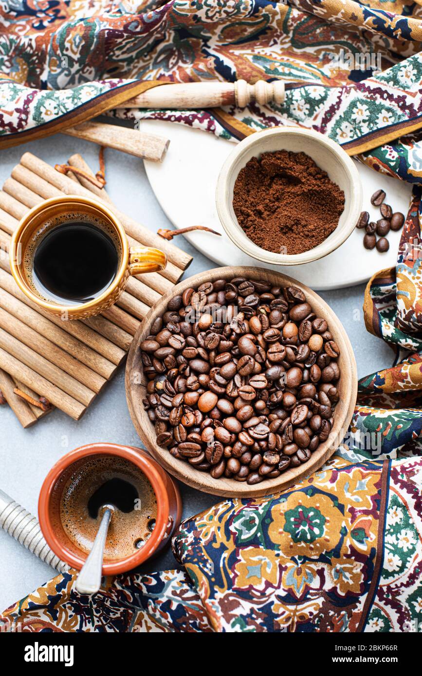 Vue aérienne d'un bol de grains de café, à côté du café moulu, d'une tasse de café et d'un foulard à motifs. Banque D'Images