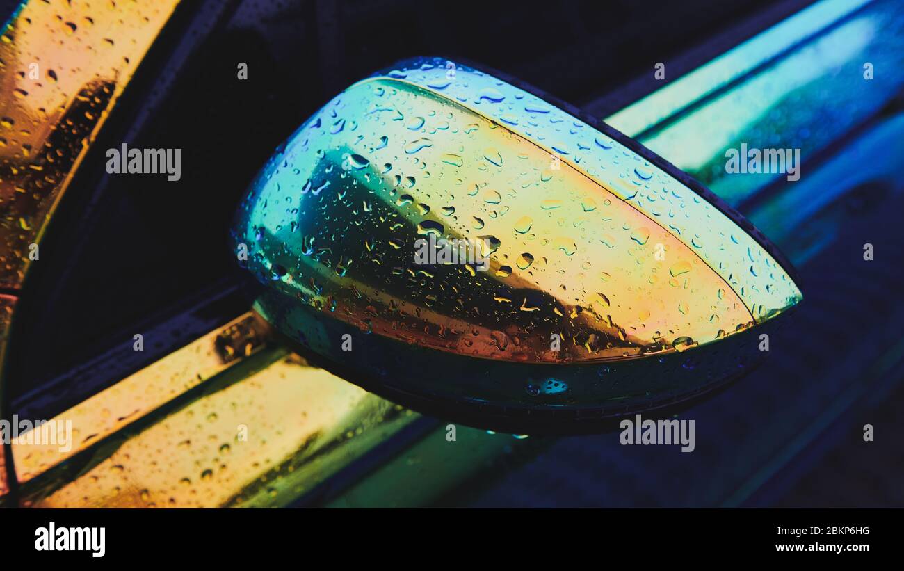 Voiture holographique couleur caméléon après la pluie. Rétroviseur latéral avec gouttes d'eau. Emballage de voiture. Photo grand format. Banque D'Images