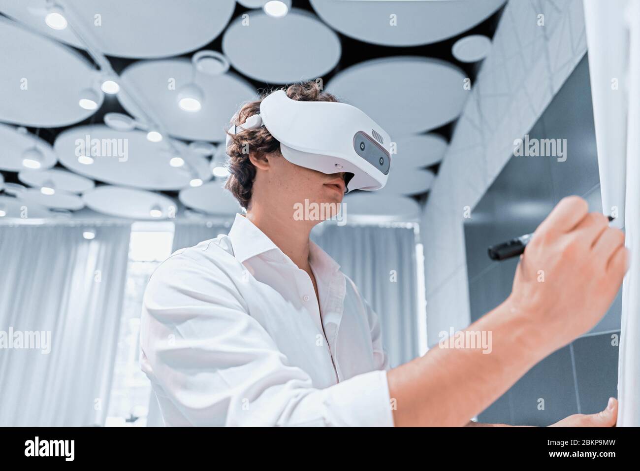 Homme portant des lunettes de réalité virtuelle dans le bureau de travail en collaboration moderne, répétant son discours lors de la présentation avec des téléspectateurs en ligne. Distance sociale, M. En ligne Banque D'Images