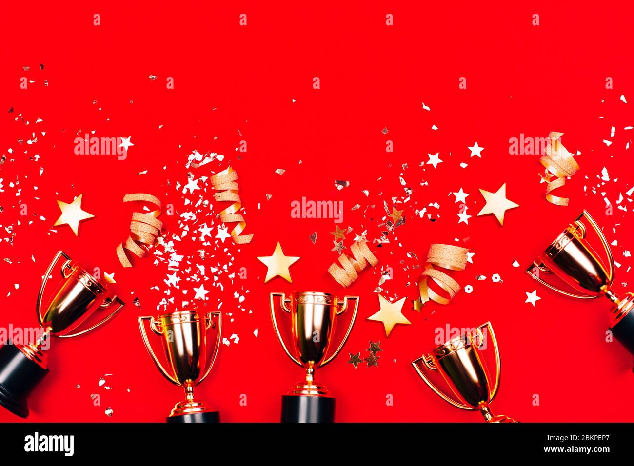 Trois coupes dorées avec confetti sur fond rouge. Style plat. Concept de concours. Banque D'Images