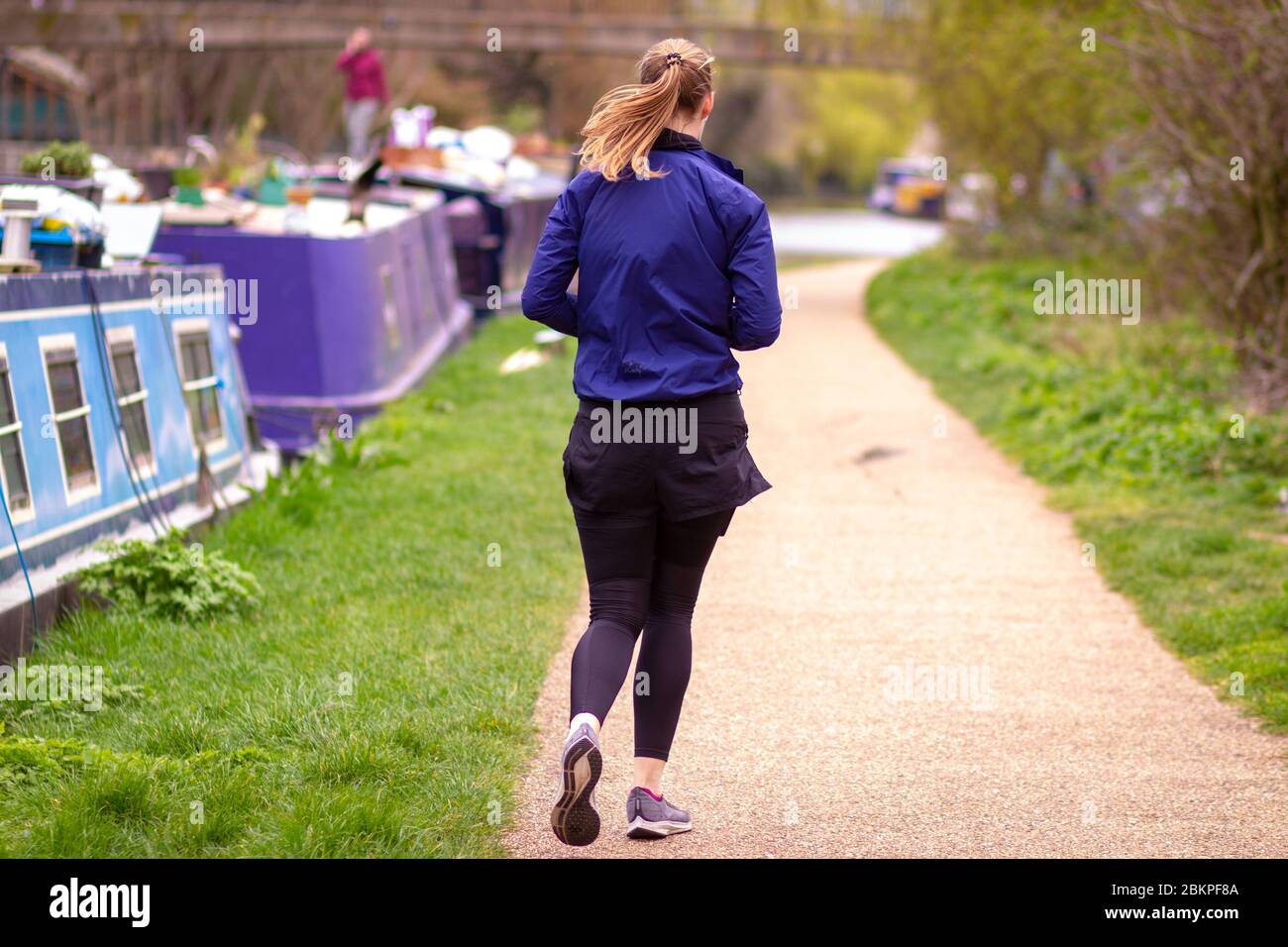 Grande femme sportive qui fait du jogging le long de la piste de remorquage à Hackney, Londres, Royaume-Uni Banque D'Images