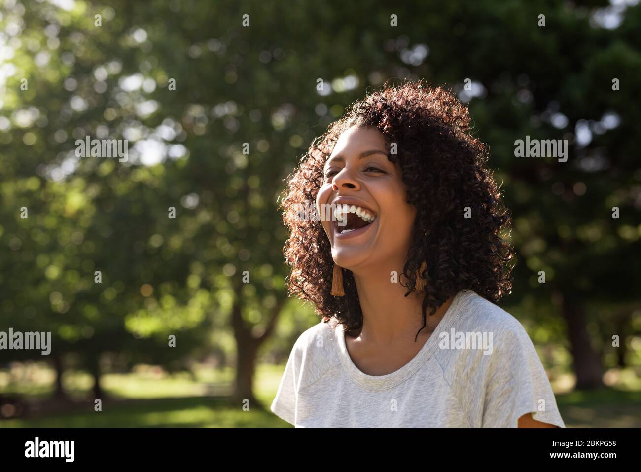 Rire jeune femme profitant d'une journée ensoleillée dans le parc Banque D'Images
