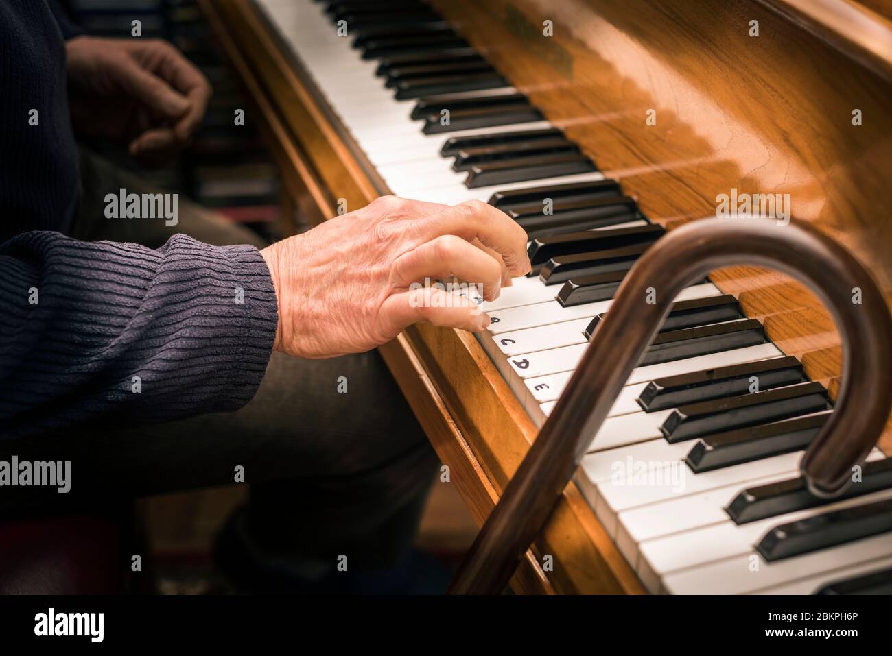 Main d'un homme âgé au piano et bâton de marche ayant une leçon de piano.  Concept: Activité de vieillesse, stimulation, apprentissage, jamais trop  vieux, maintien jeune Photo Stock - Alamy