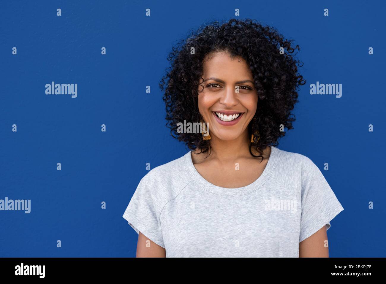 Jeune femme souriante debout sur fond bleu coloré Banque D'Images