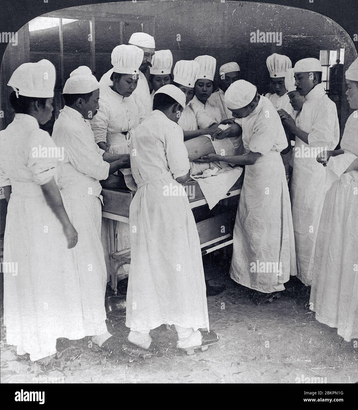 [ 1900 Japon - chirurgie pendant la guerre russo-japonaise ] — UNE équipe médicale japonaise est sur le point d’opérer sur un soldat russe blessé dans une salle d’opération de l’hôpital des prisonniers de Matsuyama, préfecture d’Ehime, pendant la guerre russo-japonaise (1904-1905). Vers 1904 (Meiji 37). chaîne stéréo du xxe siècle. Banque D'Images