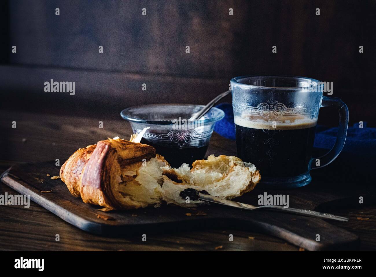 Petit déjeuner avec café, croissant et confiture, avec un fond sombre Banque D'Images