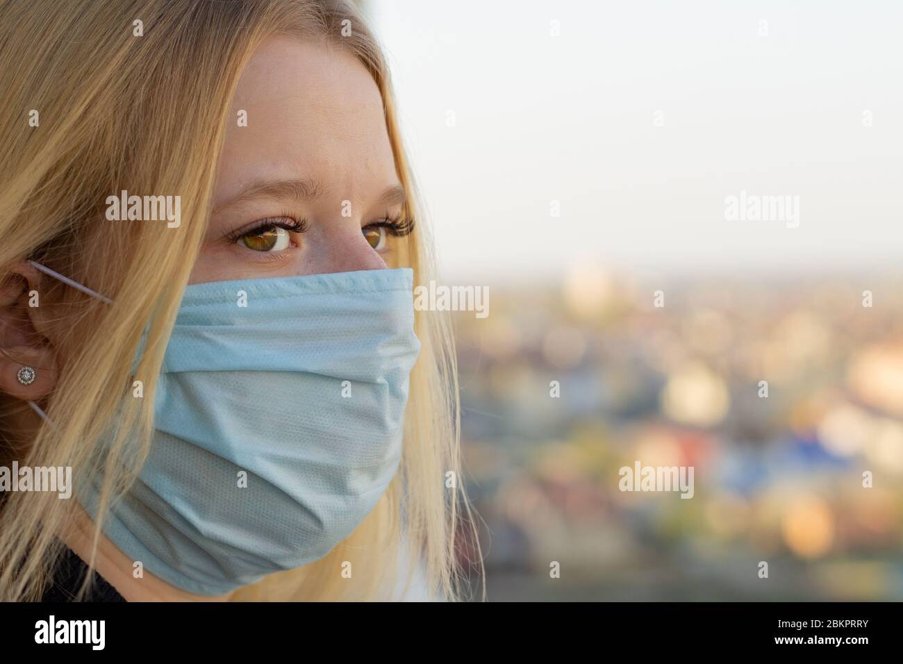 Portrait de jeune femme avec masque médical, fond de ville flou. Concept covid-19 prévention pandémie mondiale de coronavirus Banque D'Images