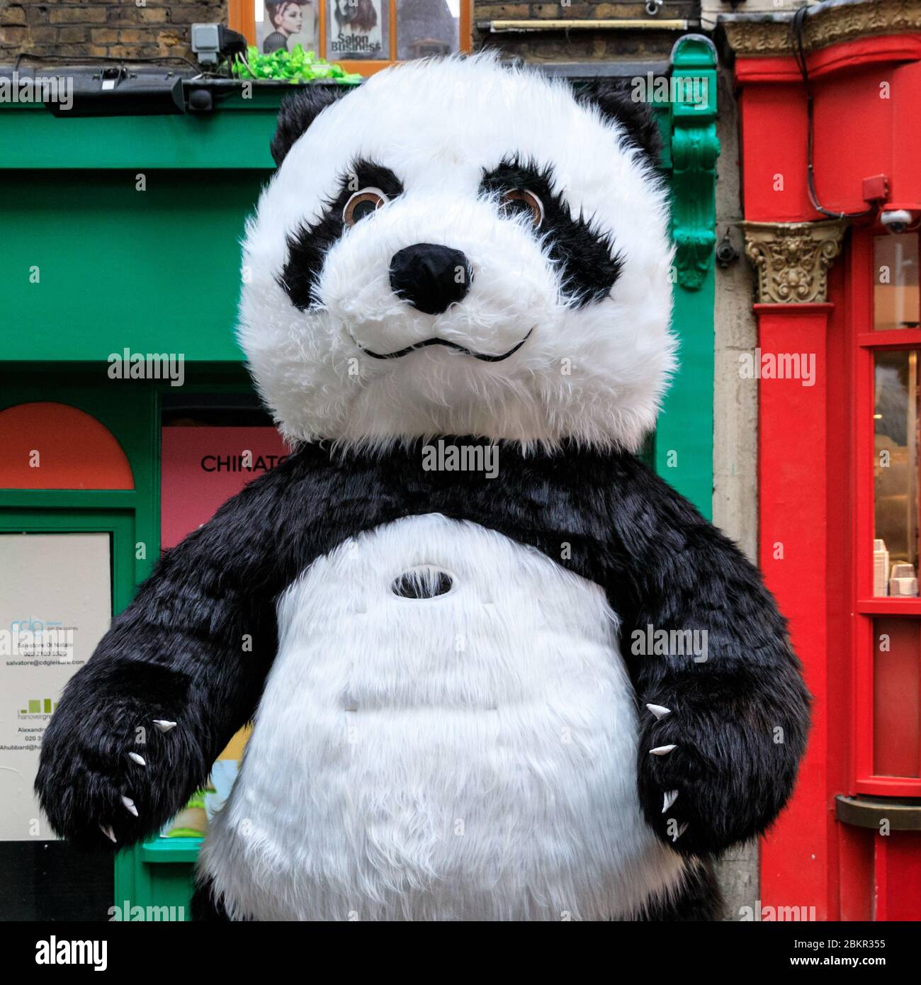 Un personnage de Panda géant devant les boutiques et les restaurants de Wardour Street dans Chinatown, Soho, Londres, décoré pour le nouvel an chinois Banque D'Images